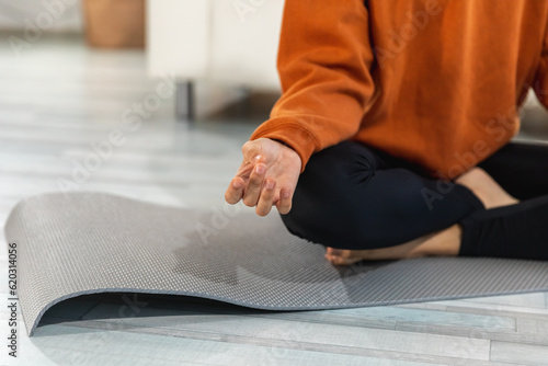 Yoga mindfulness meditation. Woman hands in chin mudra gesture. African girl practicing yoga at home. Woman sitting in lotus pose on yoga mat meditating relaxing indoor. Girl doing breathing practice