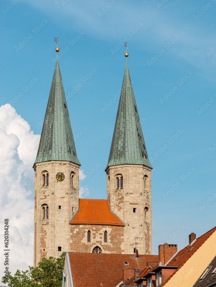 Sights of the old town of Braunschweig, Germany. Two medieval towers of the Church of St. Martini against the blue sky. Vertical photo with elements of historical buildings. Sights of the old town of Braunschweig, Germany. Two medieval towers of the Church of St. Martini against the blue sky. Vertical photo with elements of historical buildings.