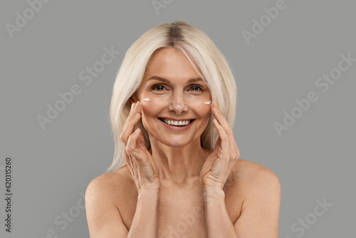 Portrait Of Beautiful Mature Woman Applying Moisturising Cream On Face