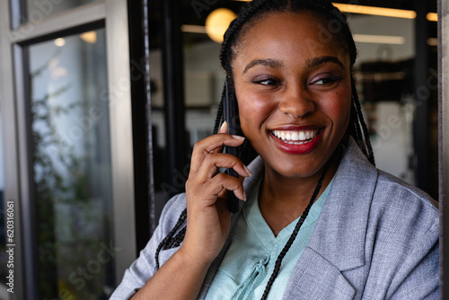 Happy plus size african american casual businesswoman talking on smartphone in office