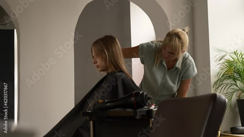 Young teenager girl sits in chair in beauty salon while hairdresser dyes hair, Wroclaw, Poland