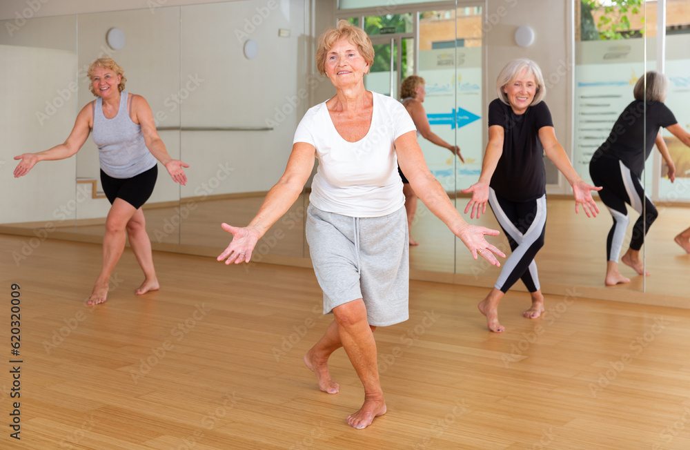 Active elderly lady visiting choreography class with group of women, learning modern dynamic dances. Concept of active lifestyle of senior generations
