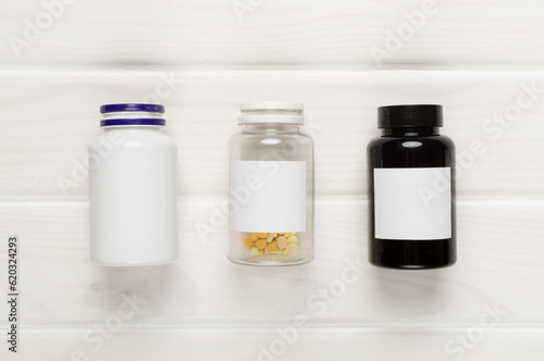 Plastic bottles with vitamins on wooden background, top view