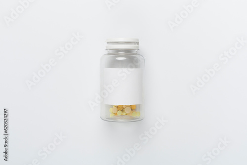 Plastic bottle with vitamins on white background, top view