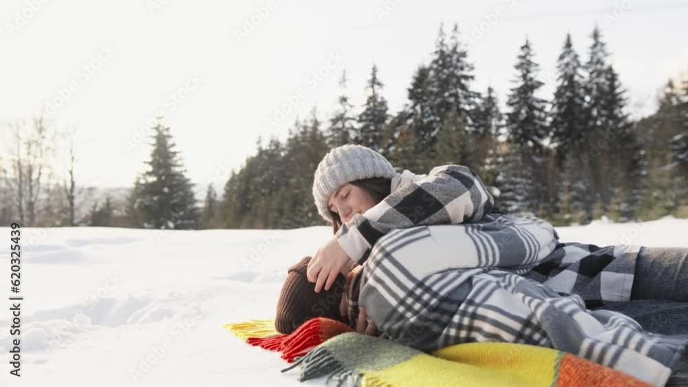 A fascinating shot capturing the magic and romance of winter, when the couple experiences unforgettable moments together lying on a blanket in the snow and basking in sun. Winter vacation in mountains A fascinating shot capturing the magic and romance of winter, when the couple experiences unforgettable moments together lying on a blanket in the snow and basking in sun. Winter vacation in mountains