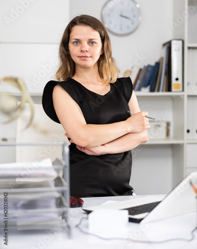 Woman accountant posing at her working table in office during workday.