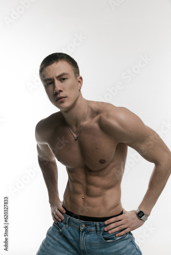 A young, sexy, athletically built man with no shirt on a gray and white background.
