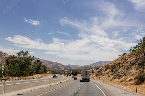 A beautiful highway among mountains with cars and trucks on sunny days. A landscape with transport. Bakersfield, California, USA - 7-22-2021