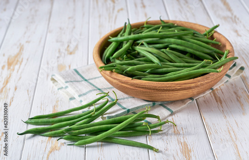 fresh green beans in a wooden bowl on a kitchen table, copy space for text.