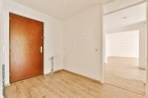 an empty room with wood flooring and white walls the door is open on the right side  to the left