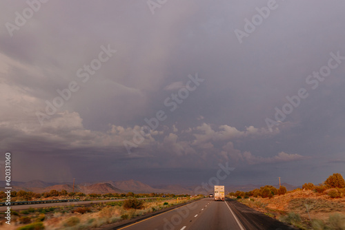 A beautiful asphalt road among hills with dry grass. A scenic landscape with highway, mountains on background and blue sky with fluffy clouds on sunny day. Phoenix, AZ, USA - 7-22-2021