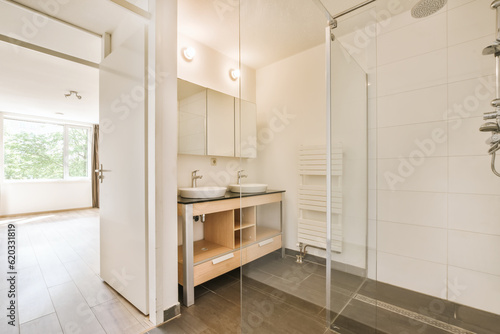 a modern bathroom with white walls and wood flooring  including a shower stall in the middle part of the room
