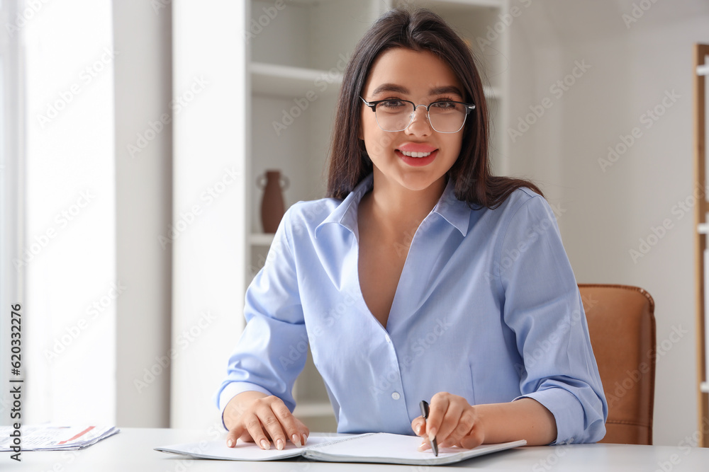 Beautiful young woman wearing glasses while working in office Beautiful young woman wearing glasses while working in office