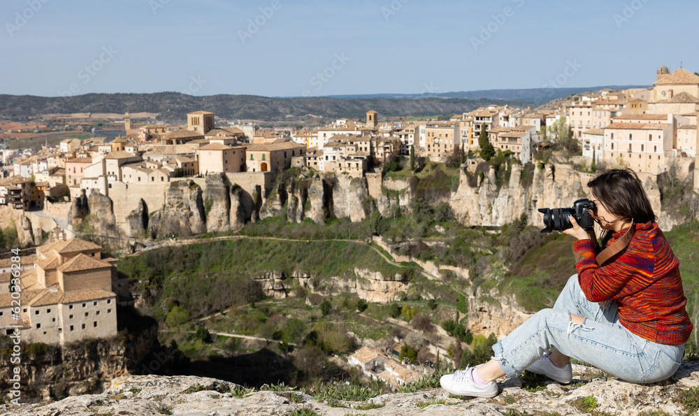 Woman tourist with camera on the background of buildings of the Spanish city of Cuenca