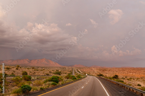 A beautiful asphalt road among hills with dry grass. A scenic landscape with highway, mountains on background and blue sky with fluffy clouds on sunny day. Phoenix, AZ, USA - 7-22-2021