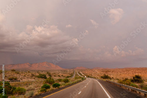 A beautiful asphalt road among hills with dry grass. A scenic landscape with highway, mountains on background and blue sky with fluffy clouds on sunny day. Phoenix, AZ, USA - 7-22-2021