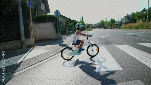 Child crossing street with bicycle. One small sportive boy at city crosswalk wearing protective helmet enjoying weekend activity photo