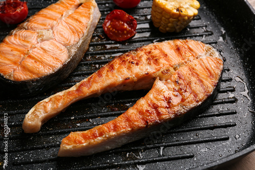 Tasty grilled salmon steaks in frying pan, closeup