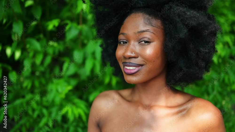 Close up slow motion portrait Beautiful young African American Black woman perfect white teeth smiling outside, sunny summer day green foliage. Facial treatment. Cosmetology, skin care and spa Close up slow motion portrait Beautiful young African American Black woman perfect white teeth smiling outside, sunny summer day green foliage. Facial treatment. Cosmetology, skin care and spa