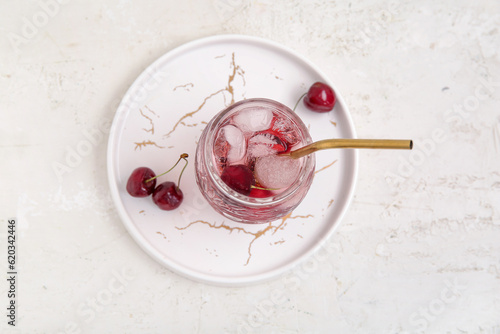 Glass of tasty cherry lemonade on white background