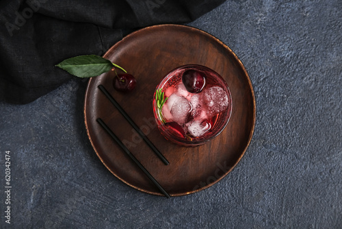 Glass of tasty cherry lemonade with rosemary on dark background