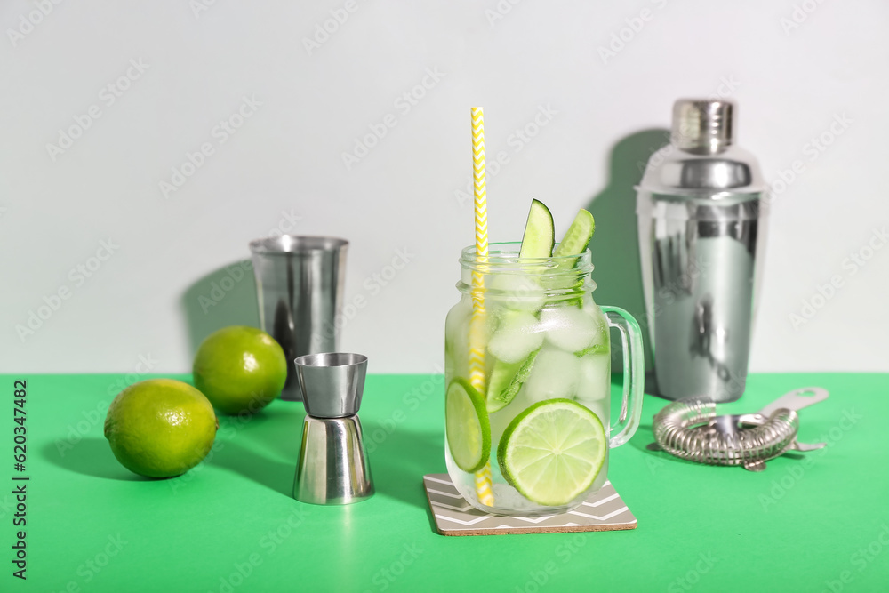 Mojito cocktail in glass jar with bartender tools on color background Mojito cocktail in glass jar with bartender tools on color background