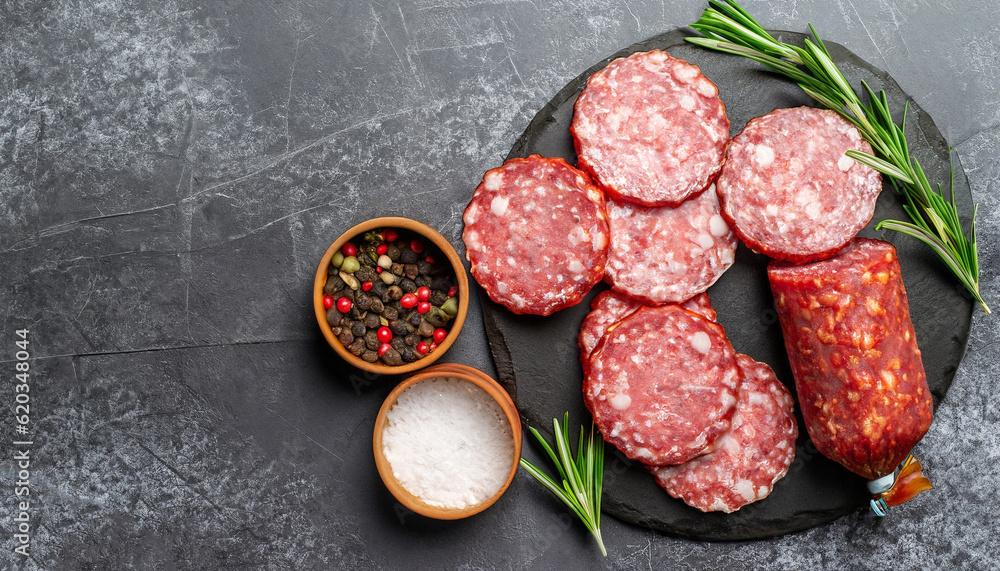 Sausage Salami with fresh rosemary and spices. stone stone background. View from above. Sausage Salami with fresh rosemary and spices. stone stone background. View from above.