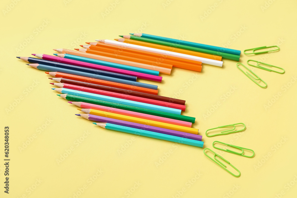Pencils and paper clips in shape of rocket on yellow background Pencils and paper clips in shape of rocket on yellow background