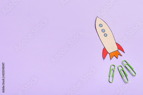Paper rocket with clips on purple background