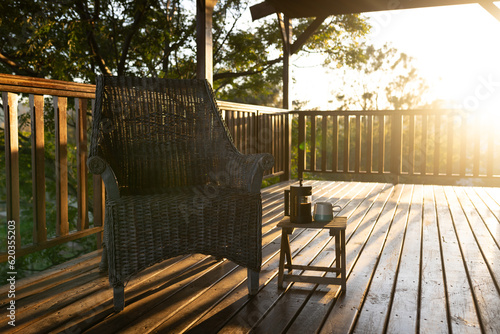 Balcony of log cabin with armchair and mug of coffee on sunny day