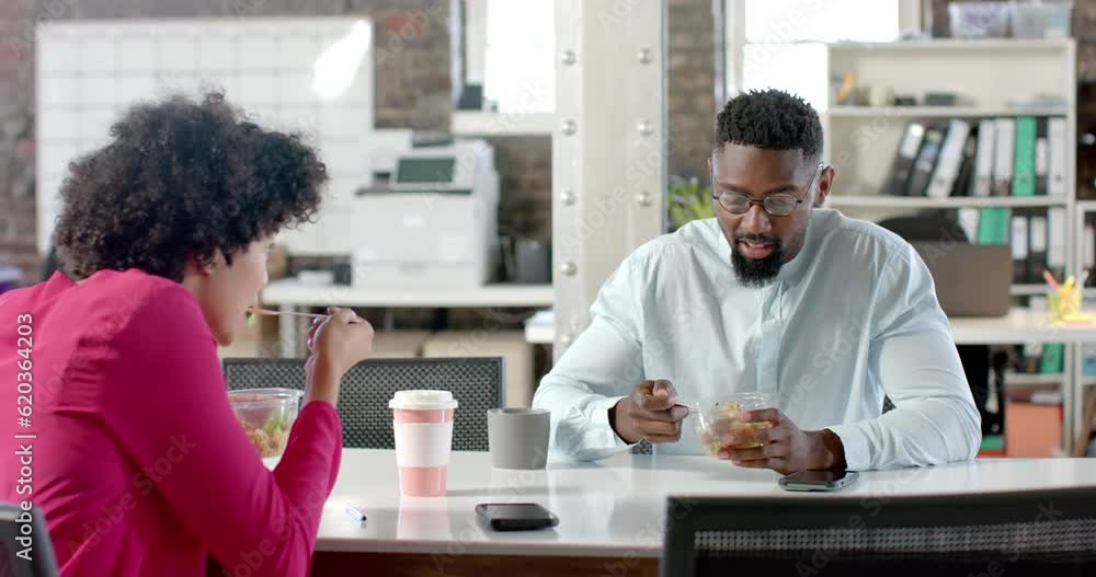 Diverse colleagues talking and having lunch at table in office in slow motion Diverse colleagues talking and having lunch at table in office in slow motion