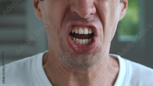 Close-up angry man swears, yells at opponent and threatens with violence. Closeup of quarrel, the mouth of angry man yells, insults the opponent and threatens with pointing finger. Quarrel concept.