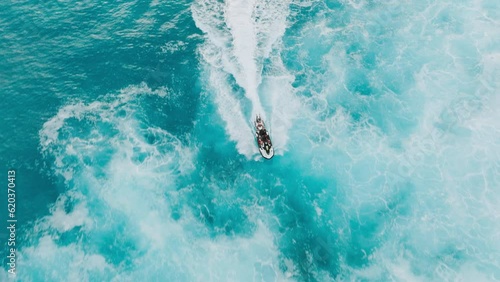 Cinematic aerial view of dangerous surfing site on Hawaii. Shore crew delivering surfers on surfboards to waves. Overhead lifeguards riding jet ski to pick up surfers in stormy ocean waters at sunset photo