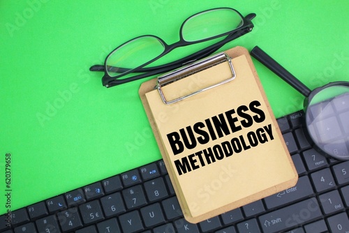 laptop keyboard, glasses and magnifying glass with the word business methodology. business concept