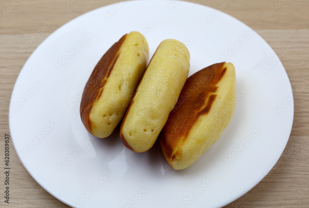 indonesian snack called kue pukis, made from eggs, and flour with cheese topping served on a plate indonesian snack called kue pukis, made from eggs, and flour with cheese topping served on a plate