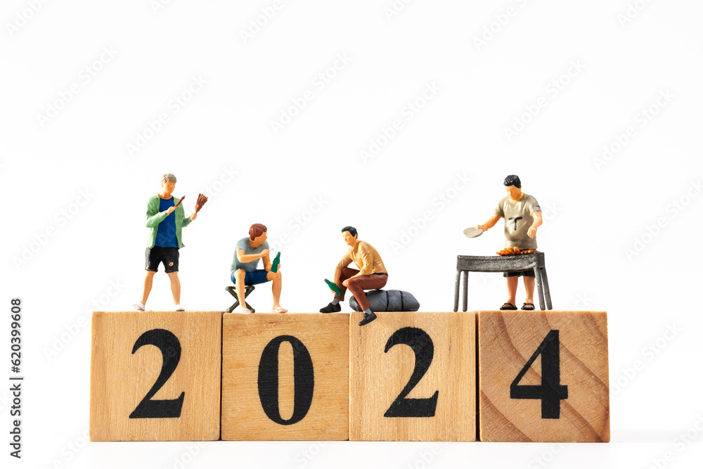 Miniature people , A joyful family enjoys New Year's celebrations with wooden block 2024 On a white background