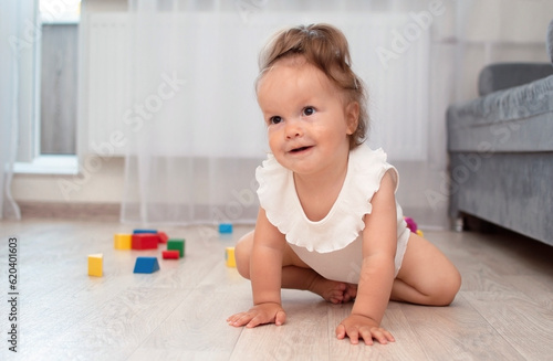 Baby crawls on floor of house exploring the world. Child learns to walk by playing indoors. Child care, parenting concept