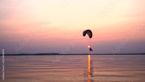 Parachute flight over the sea at sunset
