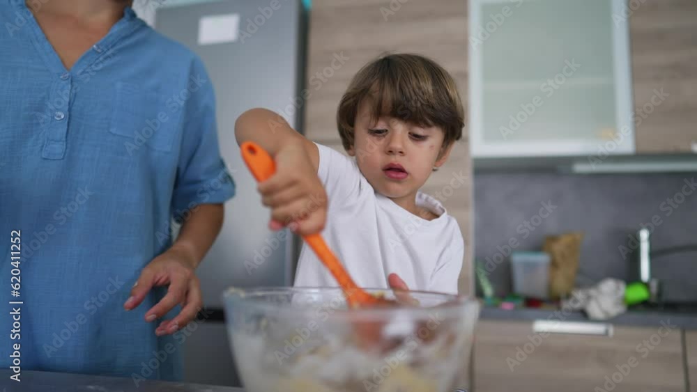 Mother and child baking together. Little boy helping parent to stir bowl with spoon. Lifestyle scene of mom and kid cooking Mother and child baking together. Little boy helping parent to stir bowl with spoon. Lifestyle scene of mom and kid cooking