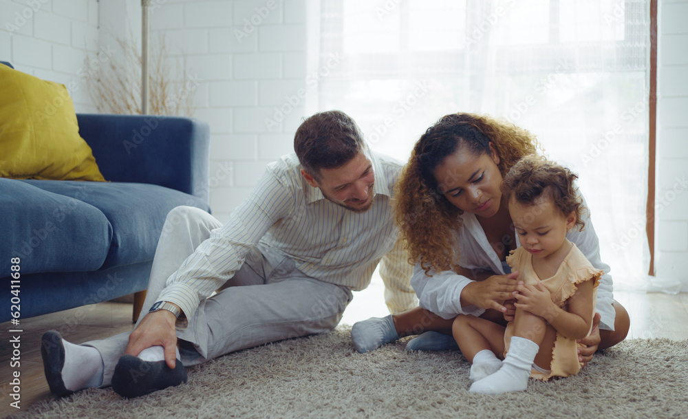Parents warmth by embracing and teasing little daughter while spend time together on floor in living room at home. Mom and Dad using spare time with baby together at warmth house. Family concept. Parents warmth by embracing and teasing little daughter while spend time together on floor in living room at home. Mom and Dad using spare time with baby together at warmth house. Family concept.