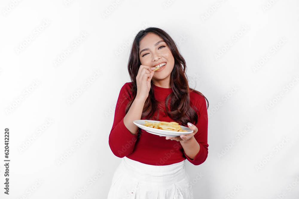 Image of smiling young Asian girl eating french fries isolated on white background
