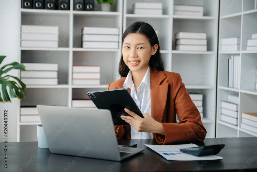 Beautiful Asian business woman typing laptop and tablet Placed at the table at the office Beautiful Asian business woman typing laptop and tablet Placed at the table at the office