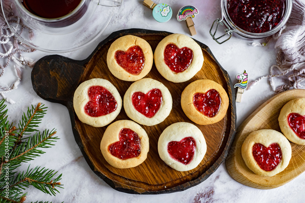 Romantic breakfast: crumbly cookies with jam. Cookies in the form of hearts on a wooden board. Close-up Romantic breakfast: crumbly cookies with jam. Cookies in the form of hearts on a wooden board. Close-up