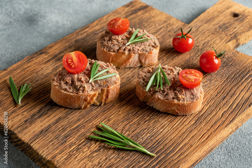 Toast with liver pate on a wooden board. Open sandwich with liver pate. Side view, selective focus.