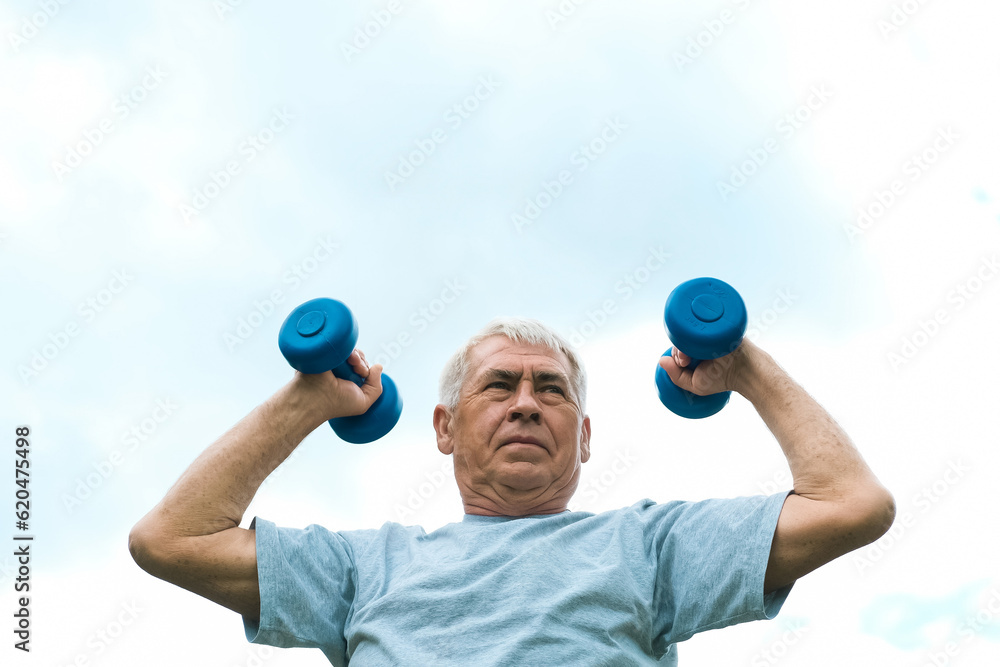 Senior man working out outdoor. Person lifting dumbbells. Old male exercising against blue sky. Healthy people lifestyle. Active sport training. Older elderly sportsman doing fitness exercise. Workout Senior man working out outdoor. Person lifting dumbbells. Old male exercising against blue sky. Healthy people lifestyle. Active sport training. Older elderly sportsman doing fitness exercise. Workout