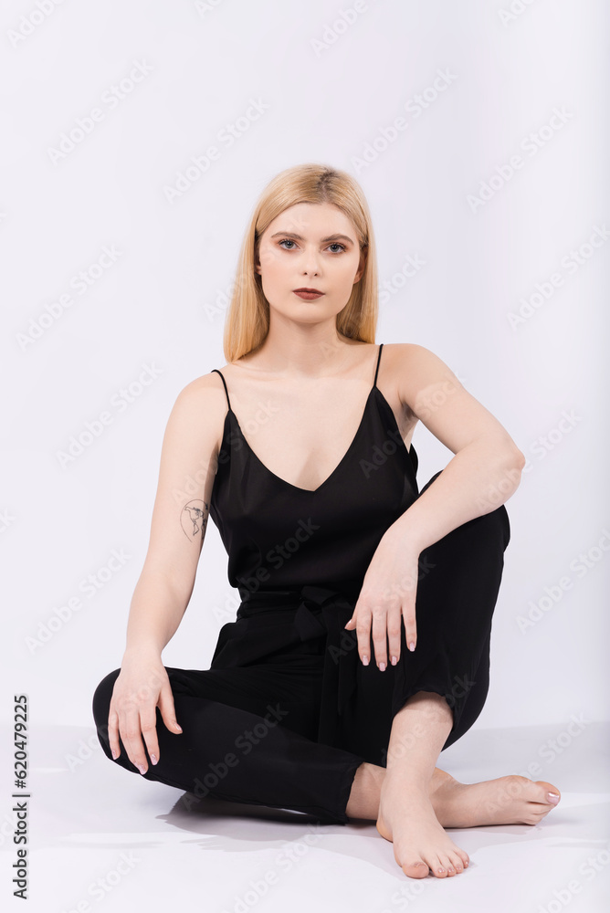 Portrait of a young and elegant girl who is sitting on the floor on a white background. Portrait of a young and elegant girl who is sitting on the floor on a white background.