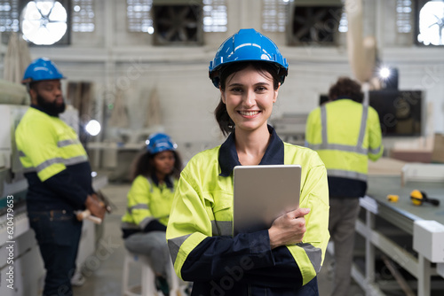 Portrait of happy smiling female engineer worker working in industry factory. Young female technician with digital tablet at work in the factory