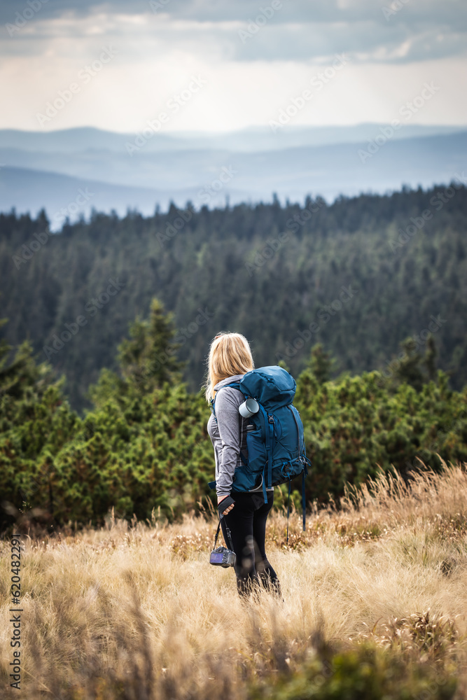 Woman photographer with backpack and camera hiking in natural parkland Jeseniky mountains. Adventure in nature