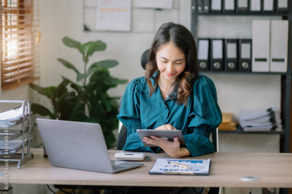 Businesswomen using tablet with laptop and document on desk in modern office. Businesswomen using tablet with laptop and document on desk in modern office.