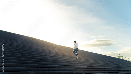 Attractive Asian woman in sportswear workout exercise jogging up on staircase at city street in the morning. Healthy girl enjoy outdoor active lifestyle do sport training fitness running in the city. photo
